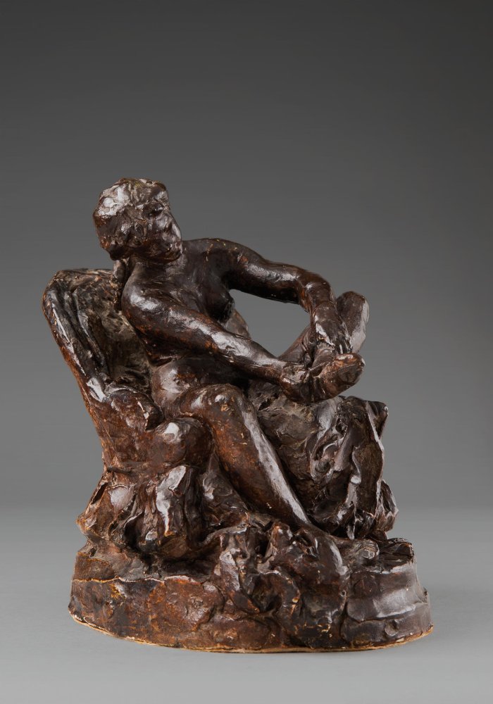 FEMME ASSISE DANS UN FAUTEUIL ET RETIRANT SON BAS